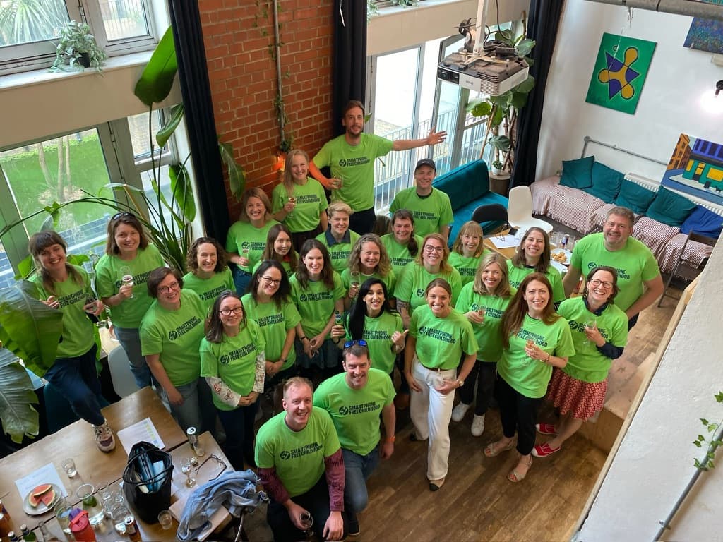 A big group of Regional Leaders in green Smartphone Free Childhood t-shirts, smiling up at the camera at a meet-up